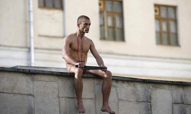 Artist Pjotr Pawlenski bei einer seiner PerformancesPavlensky sits on a wall after he cut off a part of his earlobe during his protest action titled ´Segregation´ in Moscow