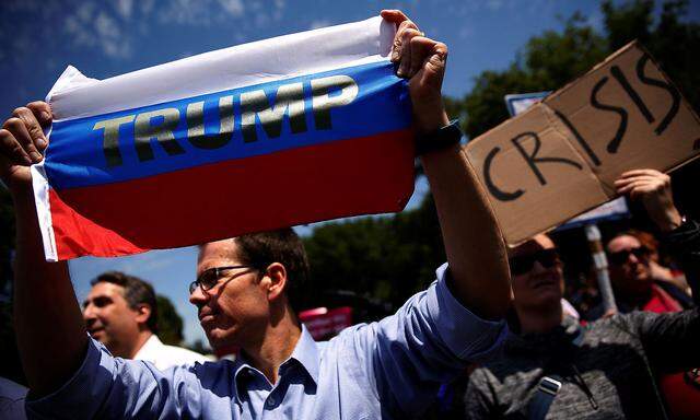 A protester holds a Russian flag with Trump´s name on it at a rally against Trump´s firing of Comey, outside the White House in Washington