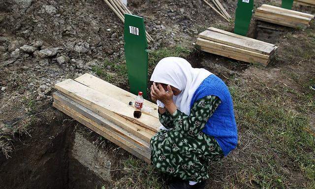 A Bosnian woman cries beside the coffin of a relative in Potocari Memorial Center, near Srebrenica