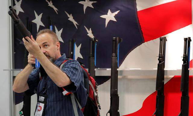 A gun enthusiast looks at a shotgun during the annual National Rifle Association (NRA) convention in Dallas, Texas