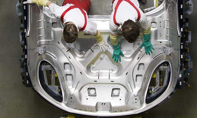 Workers carry engine hood of a Porsche Macan at the new plant in the eastern German city of Leipzig