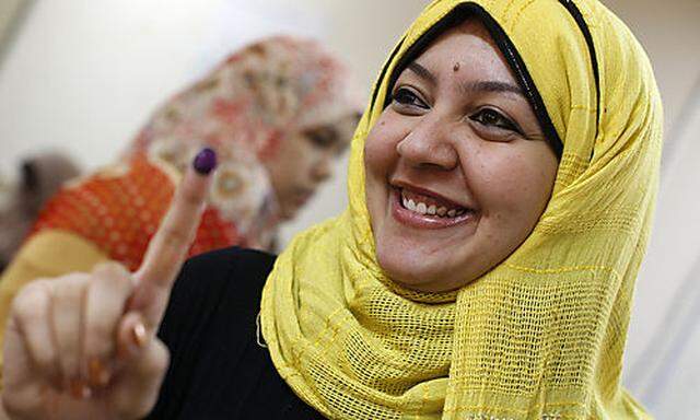 An Egyptian woman shows her inked finger after voting during the second day of presidential elections