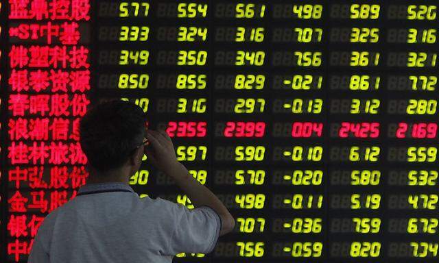 An investor reads information displayed on an electronic screen at a brokerage house in Shanghai