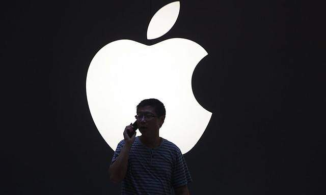 A man talks on a mobile phone in front of an Apple logo outside an Apple store in downtown Shanghai