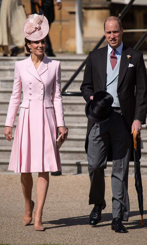 Von der Anmut seiner Frau (oder von der Sonne) geblendet, schaut Prinz William bei der Gartenparty der Queen im Garten des Buckingham Palastes ganz schön verzwickt drein. Herzogin Catherine hat hingegen gut behütet (Kreation von Juliette Botterill) den schattigen Durchblick. Ein schöner Anblick ist auch ihr knielanges rosa Mantelkleid von Alexander McQueen mit Faltenrock. Gut getarnt im Hautton sind ihre Füße (Pumps von Gianvito Rossi) und ihre Tasche (Clutch von Loeffler Randall). Eine Diana-Hommage in Form der Perlenohrringe durfte auch hier nicht fehlen.