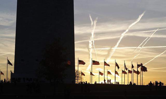 People watch the sunset from the base of the Washington Monument in Washington