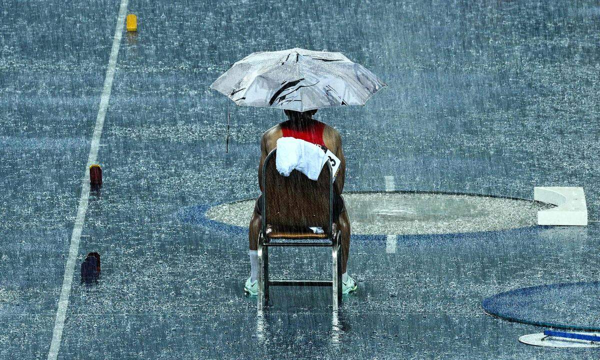 8. Mai. Der Thailänder Patsapong Amsam-ang wartet unter einem Regenschirm während einer Unterbrechung aufgrund starker Regenfälle im Stabhochsprung-Finale der Männer bei den 32. Südostasienspielen (SEA Games) in Phnom Penh.