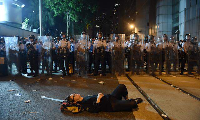 Ein Demonstrant legt sich in Hongkong vor der Polizei mitten auf die Straße.
