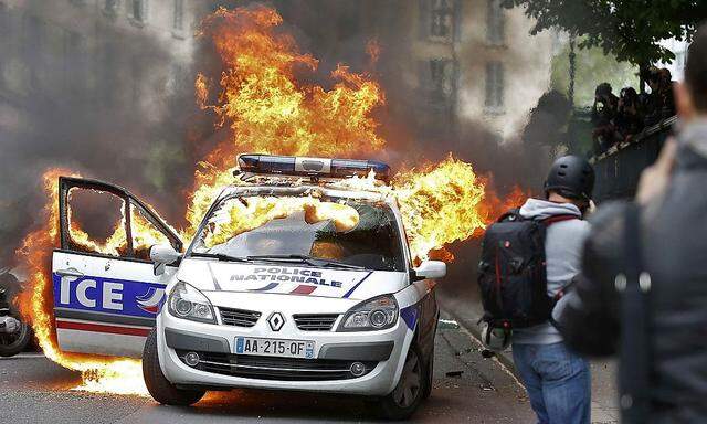 Demonstranten setzen ein Polizeiauto in Flammen.