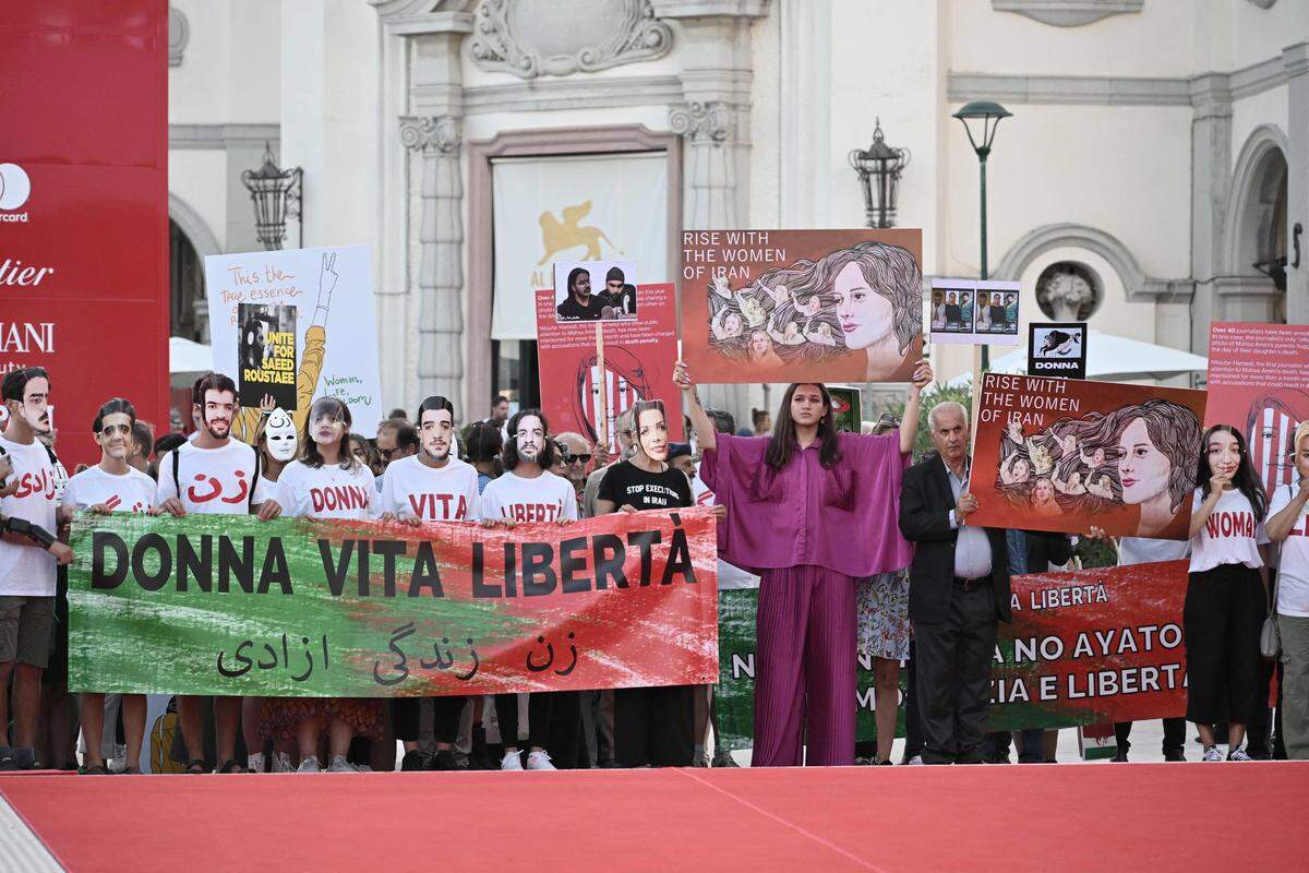 2. September. Am roten Teppich der Venediger Filmfestspiele solidarisieren sich Menschen mit Plakaten und Shirts mit iranischen Frauen. 