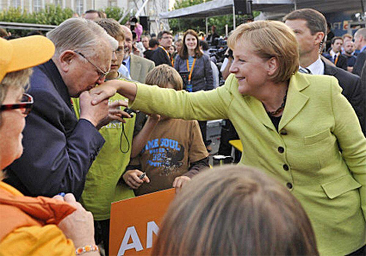 Wahlkampf ist eine wunderliche Zeit: Die Politiker, die zur Wahl stehen, buhlen auf ihren Wahlkampftouren um die Stimmen der Wähler - Hände werden geschüttelt, Reden werden geschwungen, die Nationalhymne wird gesungen. Manchmal geht man auch auf direkte Tuchfühlung: Ein Handkuss vor den Kameralinsen wird gerne entgegengenommen.  Bild: Kanzlerin Angela Merkel bei ihrer Wahlkampftour in Kassel.