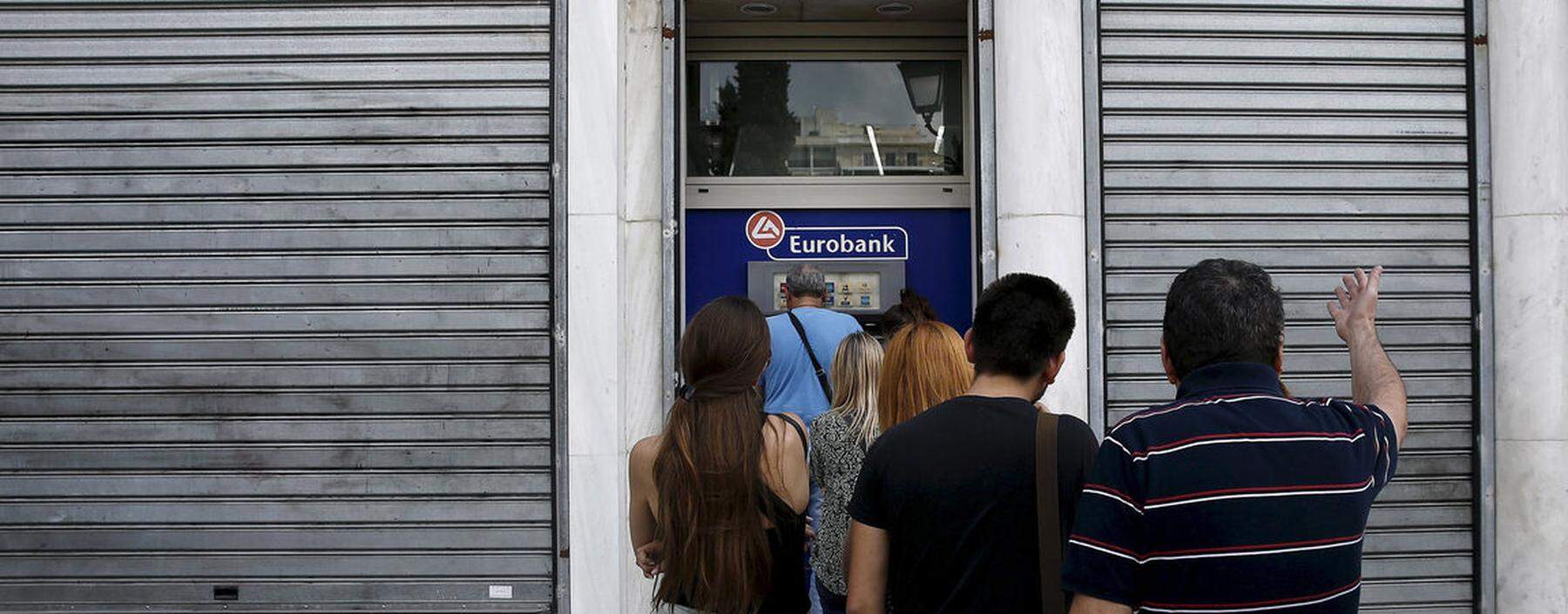 File photo of a man reacting as people line up to withdraw cash from an ATM outside a Eurobank branch in Athens