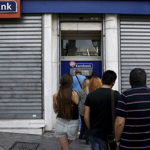 File photo of a man reacting as people line up to withdraw cash from an ATM outside a Eurobank branch in Athens