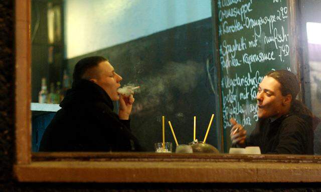 Two men smoke cigarettes inside a pub in Berlin