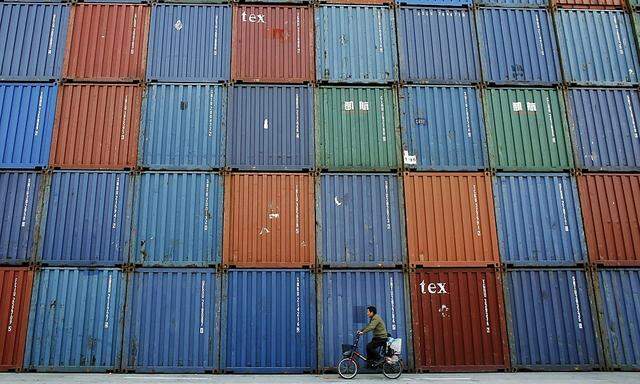 File photo of a man riding a bicycle past containers at a port in Shanghai
