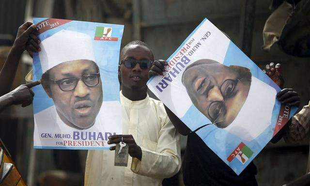 Supporters of presidential candidate Buhari hold his election posters in Kano 