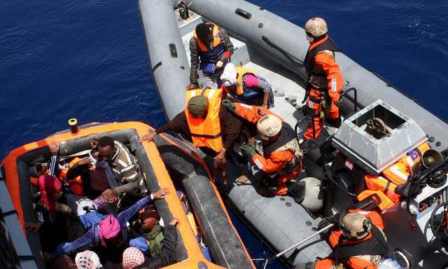 German servicemen assist some of around 200 rescued refugees boarding the frigate Hessen some 130 nautical miles off the Italian Lampedusa island