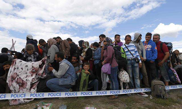 Migrants wait for buses in a makeshift camp at a collection point in the village of Roszke