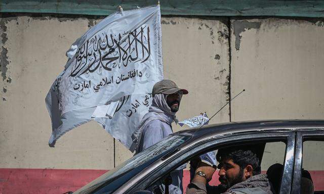 Mann trägt und verteilt Flaggen der Taliban 