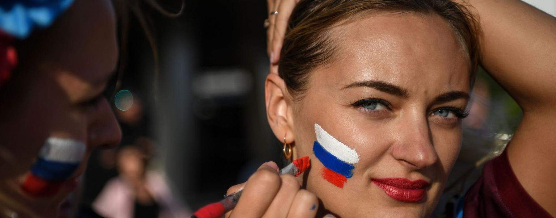 Diese Frau lässt sich eine russische Flagge auf die Wange malen. Nach der Farbenfolge könnte es auch eine slowakische sein. Die tschechische hat dieselben Farben, aber in anderer Form.