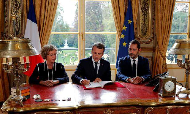 French President Emmanuel Macron signs documents in front of the media to promulgate a new labour bill in his office at the Elysee Palace in Paris