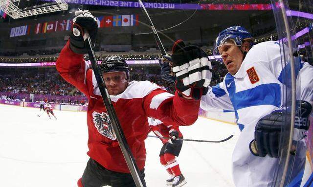 Austria's Pock and Finland's Jokinen battle in the corner during the third period of their men's preliminary round ice hockey game at the Sochi 2014 Winter Olympic Games