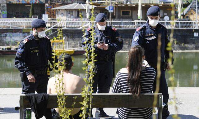 Polizeibeamte führen Aufklärungsgespräche und Personenkontrollen am Donaukanal in Wien durch.