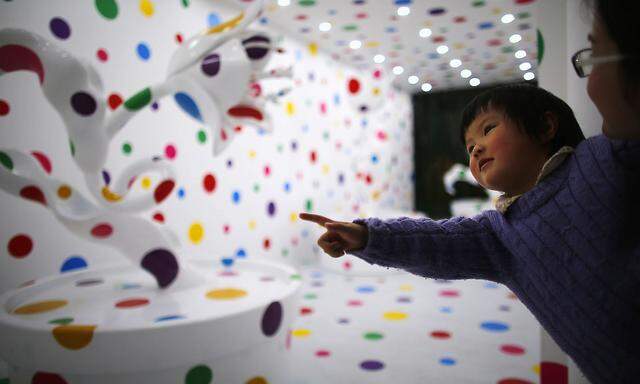 A woman holds child as they visit art exhibition ´A Dream I Dreamed´ by Japanese artist Yayoi Kusama at Museum of Contemporary Art of Shanghai