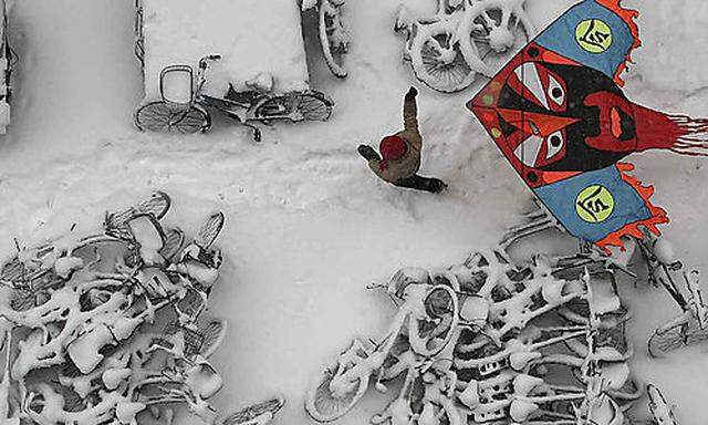 In this photo taken Monday, Jan. 4, 2010, a child flies a kite at a snow-covered bicycles parking pla