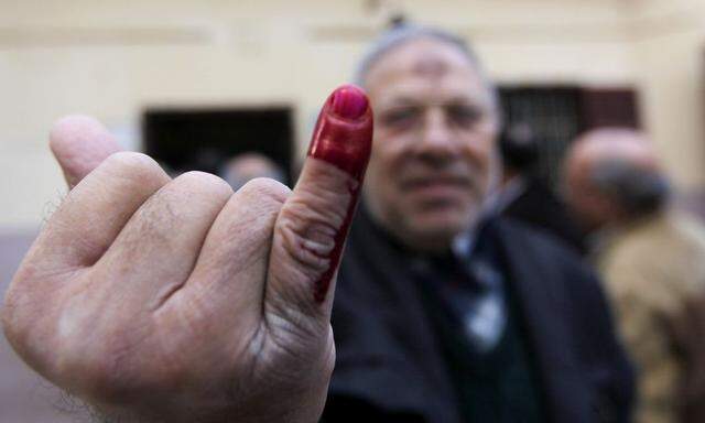 An Egyptian man shows his ink-stained finger after voting during a referendum on the new Egyptian constitution at a polling station in Cairo