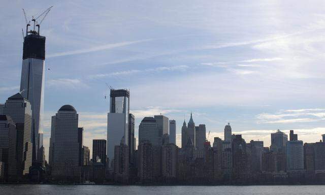 The skyline of lower Manhattan is seen as cranes lift pieces of the spire up One World Trade Center in New York