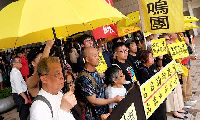 Pro-democracy supporters hold yellow umbrella to support leaders of Occupy Central activists, outside the court, in Hong Kong