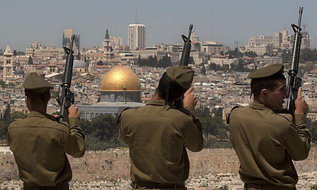 Israeli soldiers check their weapons following a Memorial Day ceremony on the Mount of Olives overloo