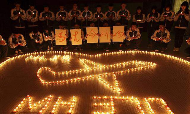 Internationale Schüler beten für die Insassen des verschwundenen Flugzeugs. Mit Teelichtern schreiben sie den Satz: 