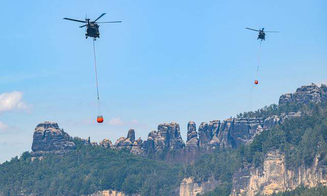 Feuerwehren in beiden Ländern sind weiterhin im Dauereinsatz. Am Samstag waren bei der Brandbekämpfung 350 Leute im Einsatz. Inzwischen sind 13 Hubschrauber für Löschflüge vor Ort.