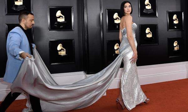 Assistenz benötigte auch Dua Lipa. An der langen Schleppe ihrer Atelier Versace Kreation hatte Mann schwer zu tragen.