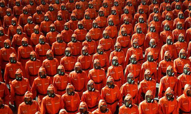 Orange Ganzkörperanzüge und Gasmasken - eine nordkoreanische Spezialeinheit sorgt für Spekulationen im Ausland. 