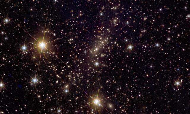 Galaxienhaufen Abell 2390: Auf dem Bild sind viele durch Gravitationslinsen verursachte Merkmale zu sehen, darunter der riesige Bogen einer weit entfernten roten Galaxie. 