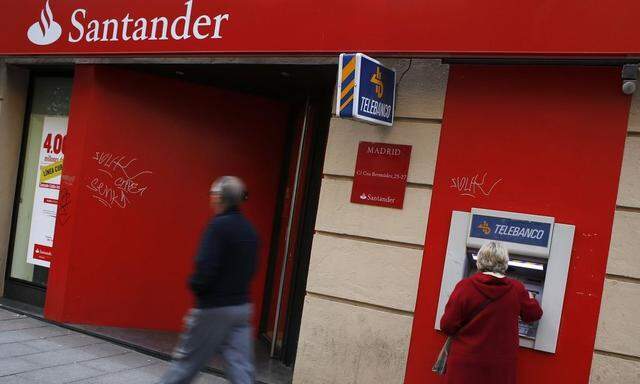 A woman uses an ATM machine at a Santander bank branch in Madrid