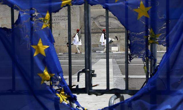 Presidential guards are framed through a burned EU flag in front of the Tomb of the Unknown Soldier by the parliament in central Syntagma square in Athens