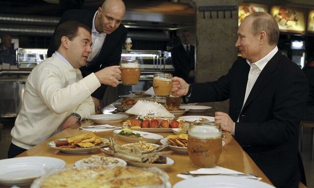 File photo of Russian President Medvedev and PM and President-elect Putin toasting with beer during a visit to a restaurant in Moscow