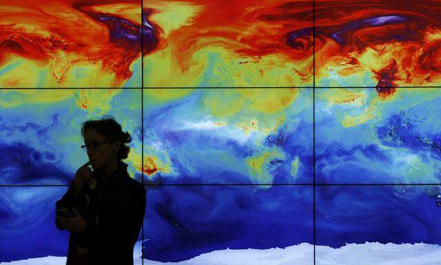 A participant is pictured in front of a screen projecting a world map during the World Climate Change Conference 2015 (COP21) at Le Bourget