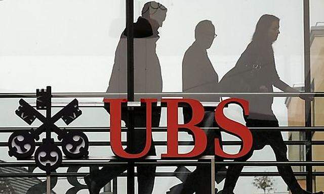File photo of people walking behind the logo of Swiss bank UBS in Zurich