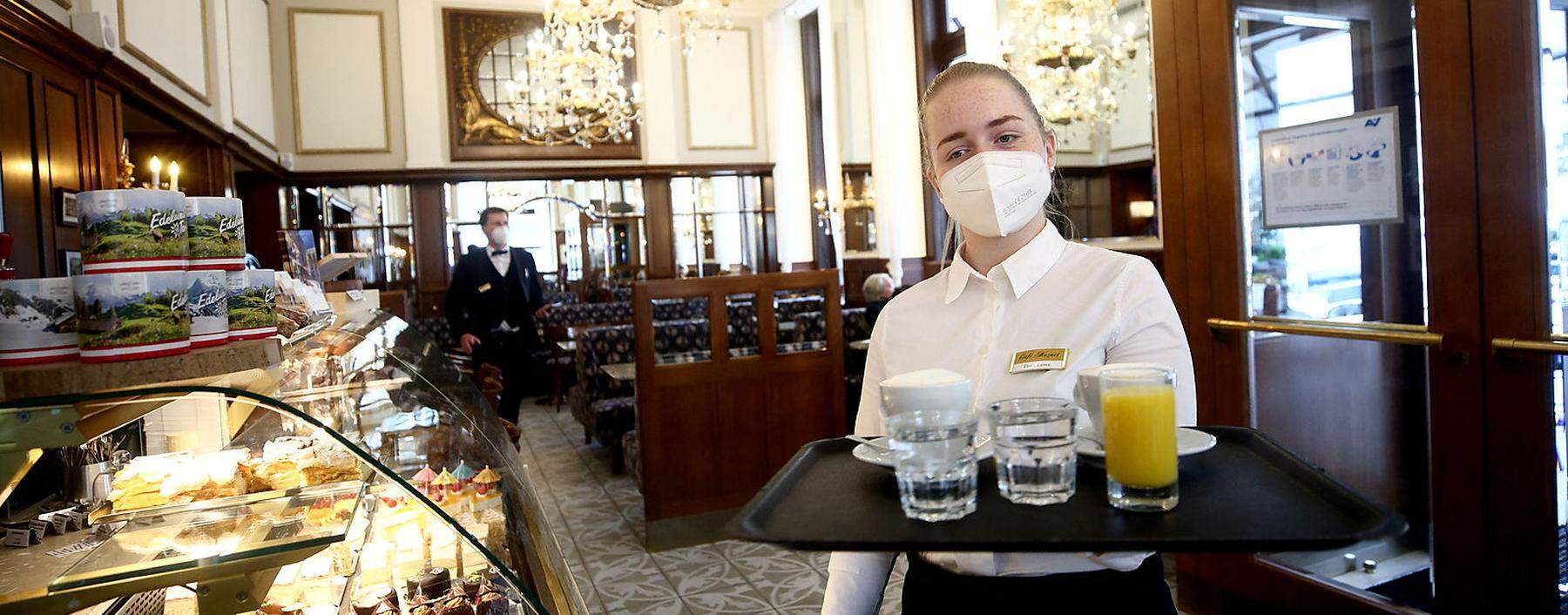 A waiter carries a tray with coffee and juice inside Cafe Mozart in Vienna