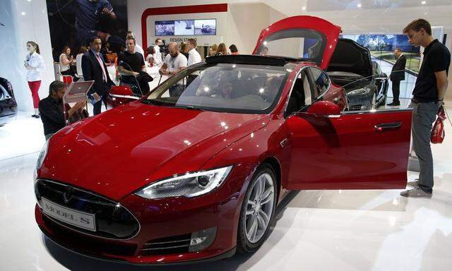 Visitors look At a Tesla Model S car displayed on media day at the Paris Mondial de l'Automobile