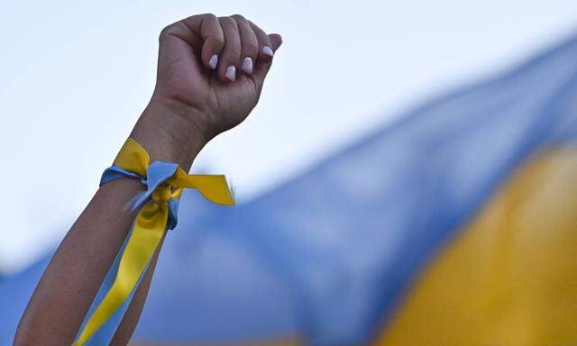 Die Solidaritätskundgebungen für die Ukraine halten an, wie hier in Krakau, Polen, wo ein Mann eine Schleife in den ukrainischen Landesfarben trägt