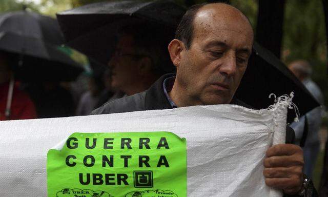 A taxi driver holds a banner during a protest held by licensed taxi drivers against taxi-hailing apps that they fear will flush unregulated private drivers into the market, in Madrid