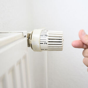 Man's hand adjusting close to a radiator making the sign with the fingers of money, saving.