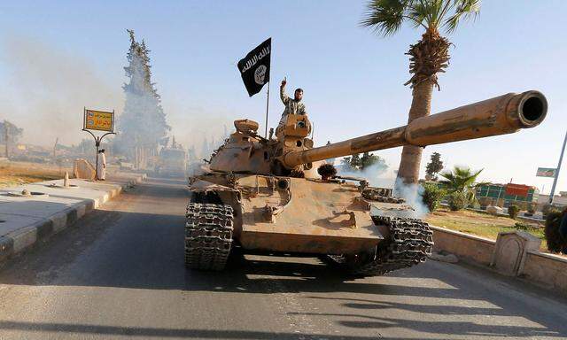 FILE PHOTO -  Militant Islamist fighters on a tank take part in a military parade along the streets of northern Raqqa province