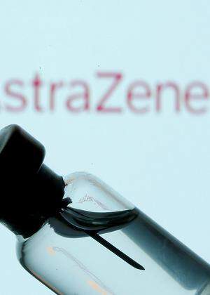 FILE PHOTO: Vial and sryinge are seen in front of displayed AstraZeneca logo